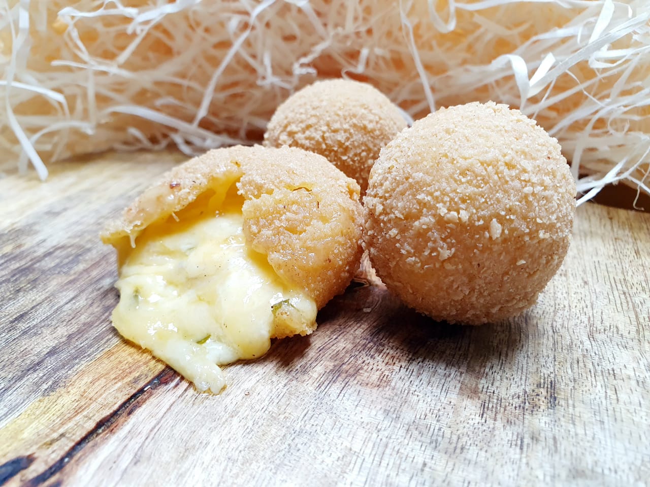 Crumbed jalapeño cheese balls, one broken open to show melted cheese