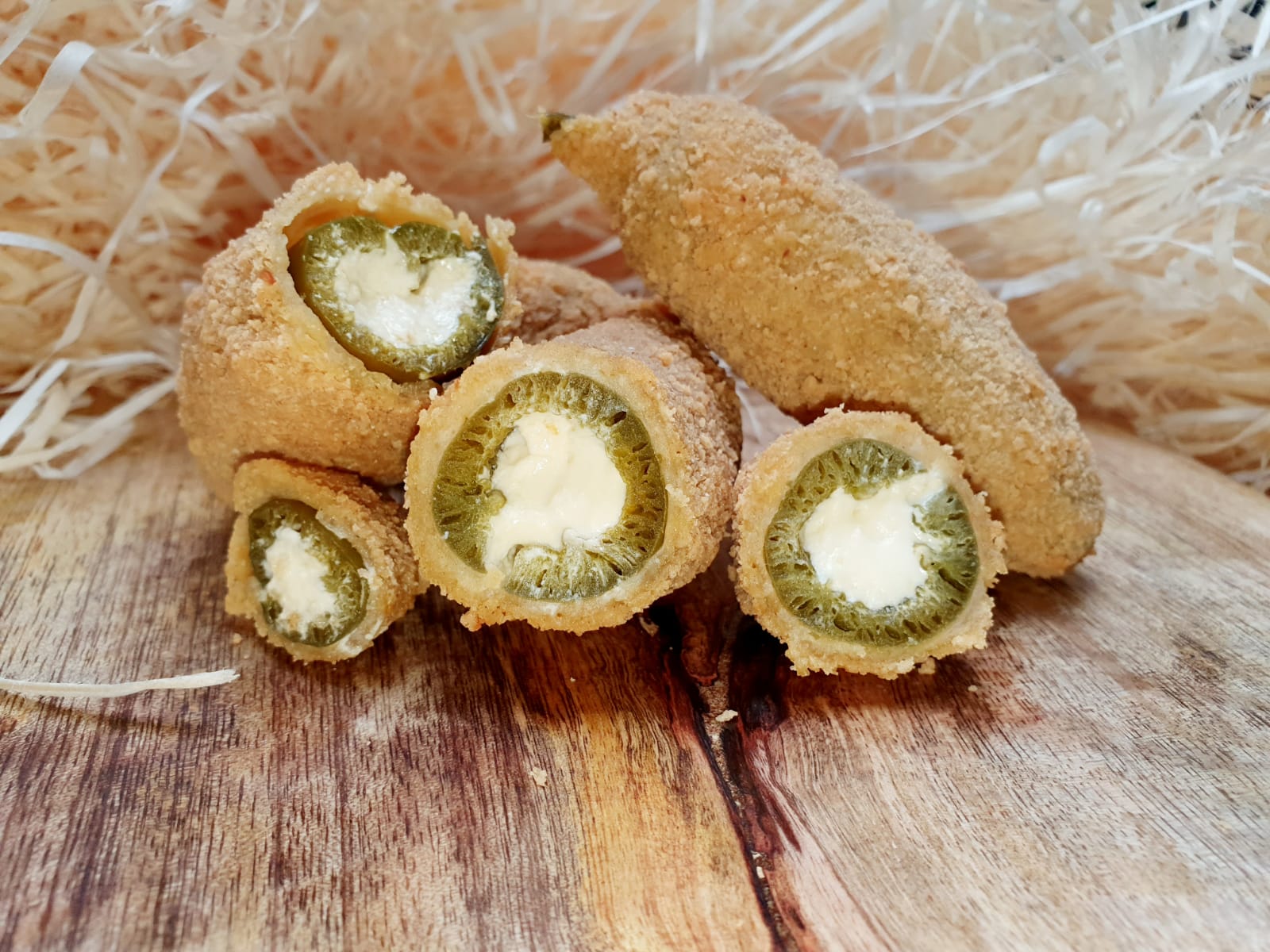 Crumbed jalapeño poppers cut open to show the cream cheese filling